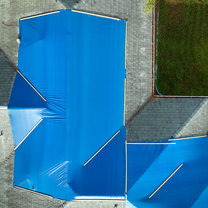 Top view of leaking house roof covered with protective tarp sheets